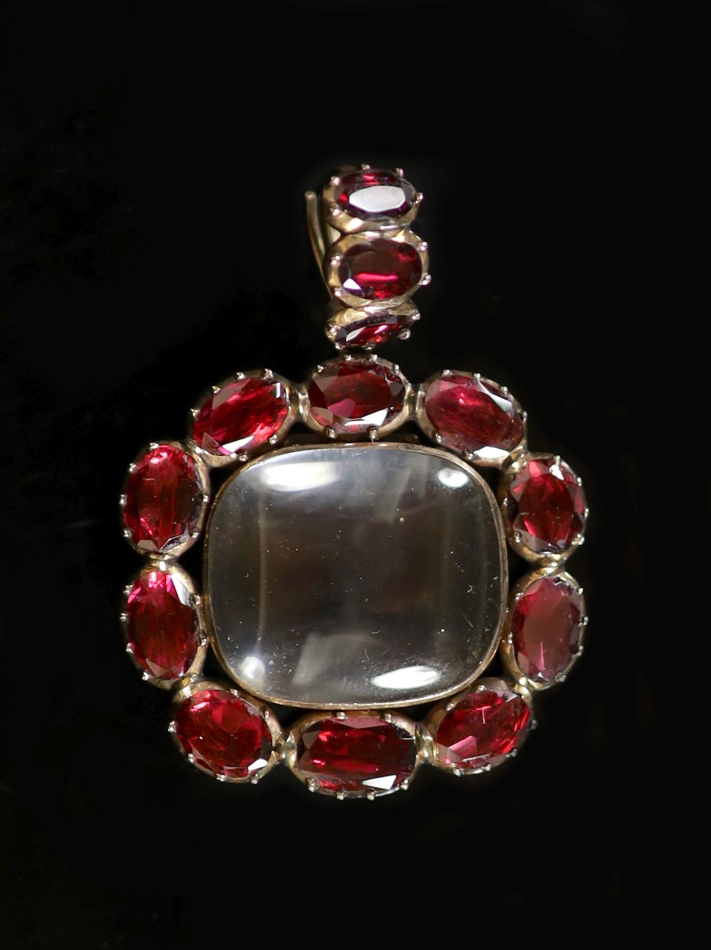 A Victorian gold, rock crystal and thirteen stone foil backed oval cut garnet set pendant